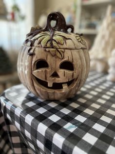 a carved pumpkin sitting on top of a black and white checkered tablecloth covered table