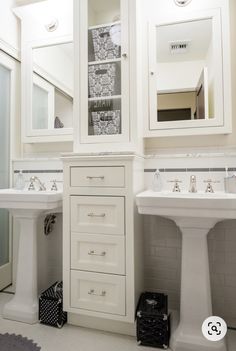 a white bathroom with two sinks and cabinets