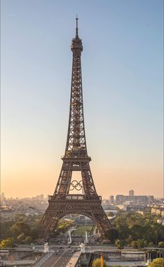 the eiffel tower in paris is lit up at sunset with olympic rings on it