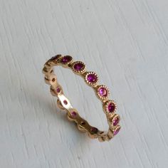 Gold Eternity ring set with Beautiful Pink Rubies. Famous for its passionate Pink-Red Color this July birthstone gemstone in one of finest and most sought after gemstones. Elegantly Set in a crown settings, Each ruby is 2mm in diameter with excellent color and clarity. This graceful Eternity ring has a dainty poise about it, getting lots of the right attention every time you wear it on its own or stack it with your other rings! Featuring between 15-22 Gemstones(Depending on ring size). Other sto Pink Sapphire Ring With Halo, Pink Sapphire Round Band Wedding Jewelry, Pink Gold Jewelry With Halo Setting, Pink Ruby Gemstone Ring For Anniversary, Pink Gemstone Eternity Band Fine Jewelry, Pink Sapphire Jewelry With Halo Design, Pink Round Cut Eternity Band Promise Ring, Pink Sapphire Halo Jewelry With Round Cut, Pink Ruby Promise Ring With Halo Setting