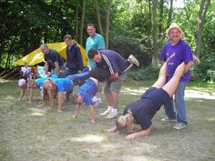 a group of people standing around each other in the grass with one person upside down