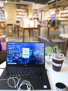 an open laptop computer sitting on top of a white table next to a cup of coffee