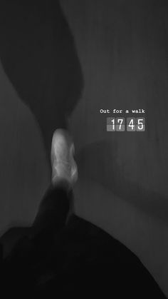 a black and white photo of a person's foot in the dark with text out for a walk