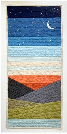 a quilted wall hanging with the night sky and stars above it, as well as mountains