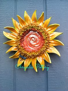 a yellow and red sunflower sitting on top of a blue door with a spiral design in the center