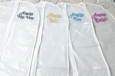 five white garment bags with embroidered name tags on them