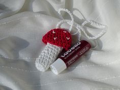 a crocheted toothbrush holder and lip balm bottle on a white sheet