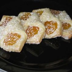 small pastries with powdered sugar on top sit in a black plate, ready to be eaten