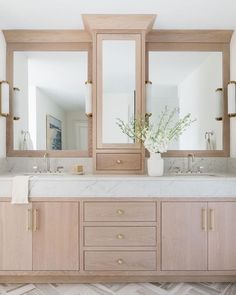 a bathroom with double sinks and large mirrors