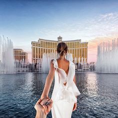 a woman in a white dress standing next to a fountain