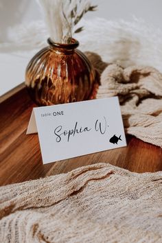 a table topped with a vase filled with flowers next to a white and brown card