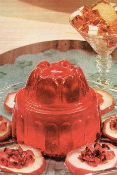 a cake on a plate with some fruit around it and a glass bowl in the background