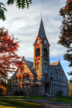 an old church with a clock tower in the middle of it's front yard