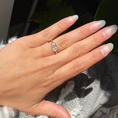 a woman's hand with a diamond ring on her left hand and white nails