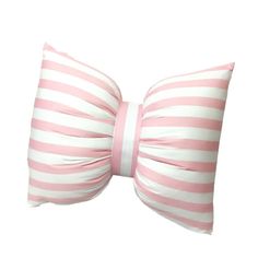 a pink and white striped pillow with a large bow on the front, sitting against a white background