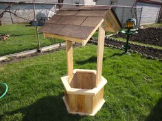 a small wooden structure in the middle of some grass with a bird house on top