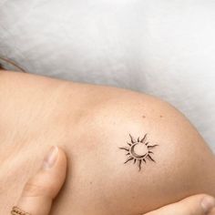 a woman with a small tattoo on her shoulder and arm, holding the sun in her hand