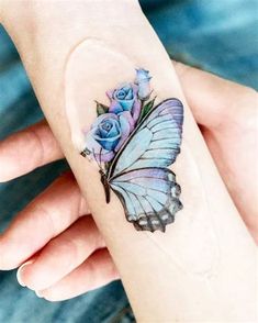 a woman's hand with a blue butterfly and roses tattoo on her left wrist