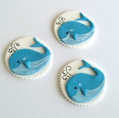 three decorated cookies sitting on top of a white table next to each other with blue icing