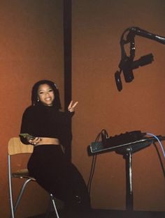 a woman is sitting in a chair with her hand up to the side and smiling