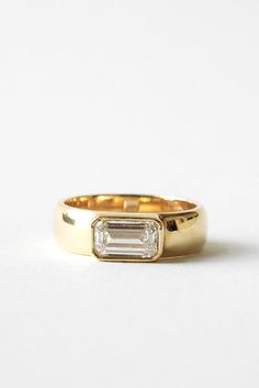 a gold ring with a baguette cut diamond in the center on a white background