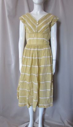 "SALE! 15% OFF! Perfect for summer days--a vintage sundress or sleeveless dress. In a mustard tone dotted swiss, it has white \"stripes\" of 1/2\" insert trim.  For the bodice, the trim is diagonal. The 4\" V- neck bodice is fitted leading to a cord bordered 6\" cummerbund.  The back is also V-shaped--7\" from nape to back.  It has 6 decorative buttons at the front. The skirt is full. It closes at the side with 12\" metal zipper. There is a slight cap at the shoulders.  No maker label Size: no s Vintage Sundress, Decorative Buttons, Sun Dress, White Trim, Metal Zipper, Dress Summer, Vintage Dress, Fitted Bodice, Full Skirt