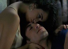 a man and woman laying next to each other on top of a bed with their eyes closed