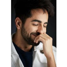 a man with his hand on his face looking down at the ground while wearing a white coat