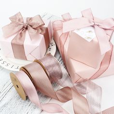 pink ribbon and gift boxes on white wooden background with text that reads larbibons we are ribbons and more