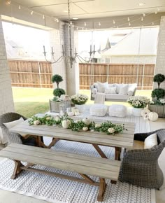 an outdoor patio decorated for fall with white pumpkins and greenery on the table