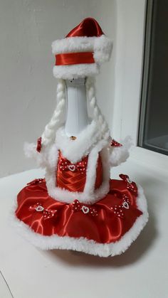 a white and red santa claus hat on top of a bottle wearing a red dress