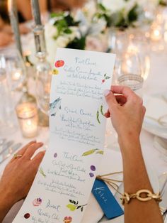 a person holding up a piece of paper with writing on it at a dinner table