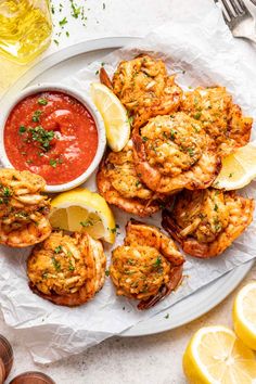 grilled shrimp with marinara sauce and lemon wedges on a white platter