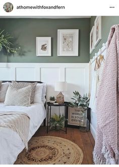 a bedroom with green walls and white headboard, rugs and pictures on the wall