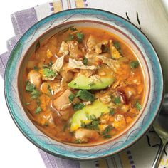 a bowl of chicken tortilla soup with avocado and cilantro