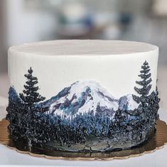 a white cake decorated with trees and mountains