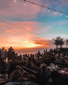 many people are sitting on the beach at sunset