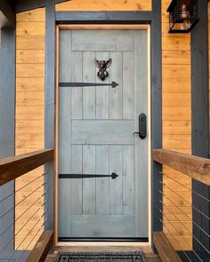 the front door of a wooden cabin with an arrow and deer head on it's side