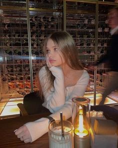 a woman sitting at a table in front of some glasses