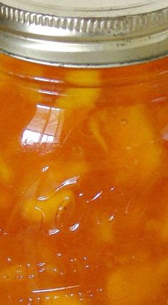 a glass jar filled with oranges sitting on top of a table