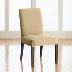 a beige chair sitting on top of a hard wood floor next to a white wall