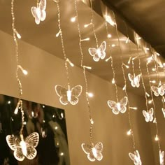 some lights that are hanging from the ceiling and butterflies on the strings in front of them