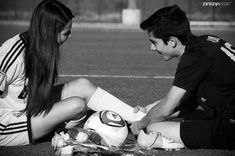 a man and woman sitting on the ground next to each other near a soccer ball