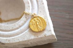 a gold necklace with an ancient coin on it