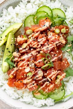 a white bowl filled with rice, cucumbers and meat on top of it