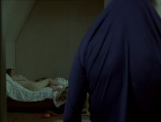 a man standing next to a bed in a room with a woman laying on it