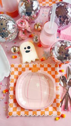 a pink table topped with plates and silverware next to disco ball decorations on top of it