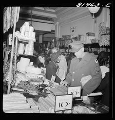 an old black and white photo of people looking at items