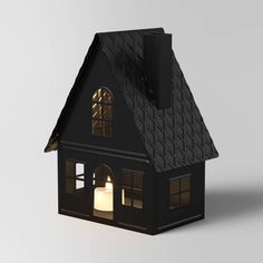 a small black house with a lit candle inside