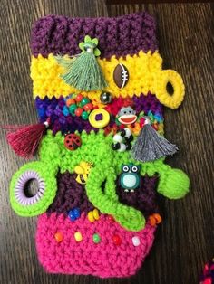 there are many crocheted items on top of the table, including a cell phone case